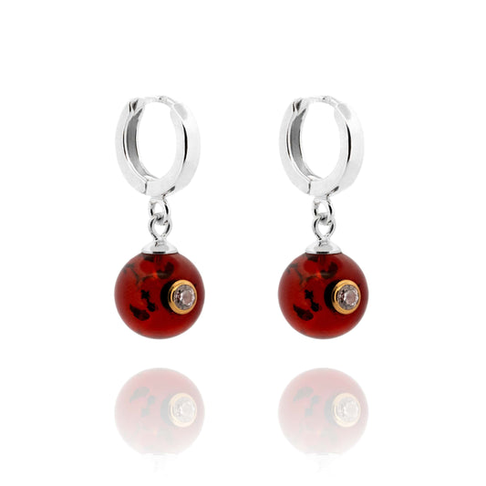 Sidabriniai auskarai su Baltijos gintaru ir cirkoniu.   Metalas - AG925 sidabras.  Apvalios formos Baltijos gintaras, su inkrustuotu cirkoniu.   Tamsaus konjako - vyšnios spalva.   Dydis: 25 x 12 mm.  Svoris: 3.1g  Gintaras su įvairiais vidiniais raštais.