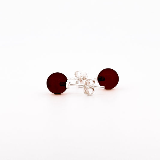 STUDS, Auskarai su natūraliu Baltijos gintaru.   Poliruotos, apvalios formos natūralaus gintaro detalės.  Gintaro diametras: 5 – 7 mm.  Išmatavimai: 5-7mm x 18 mm.  Tamsios vyšnios spalva.  Metalas: Ag 925 Sidabras.