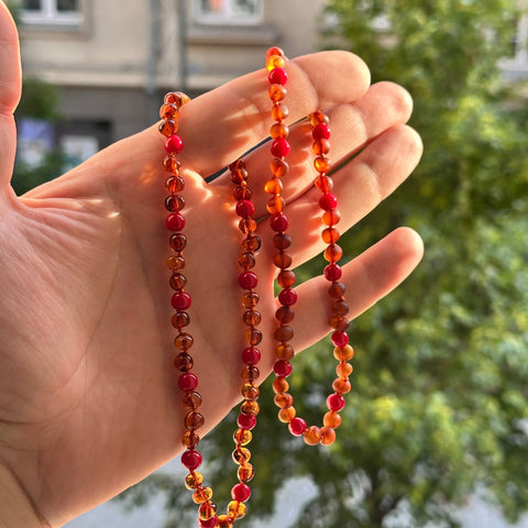 Gintaro Vėrinys Vaikams – Konjakas + Raudonasis Koralas
Šis gintaro ir akmens vėrinys vaikams spinduliuoja išskirtiniu gyvybingumu ir natūralia elegancija. Sodri konjako spalvos gintaro šiluma puikiai dera su ryškiai raudonu koralu, kuris simbolizuoja energiją, apsaugą ir gyvą emocinį ryšį. Šis derinys džiugina tiek akį, tiek širdį – tai ne tik gražus papuošalas, bet ir prasmingas aksesuaras. Karoliukai išdėstyti ritmingai: trys gintaro ir vienas koralo.

Savybės
100 % natūralus Baltijos gintaras – sodri, š