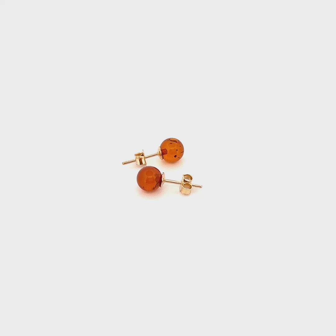 STUDS, Auksiniai auskarai - vinutės su natūraliu Baltijos gintaru.   Poliruotos, apvalios formos natūralaus gintaro detalės.  Gintaro diametras: 7 mm.  konjako spalva.  Svoris: 0,96 g. Metalas: AU585 prabos geltonas auksas. 