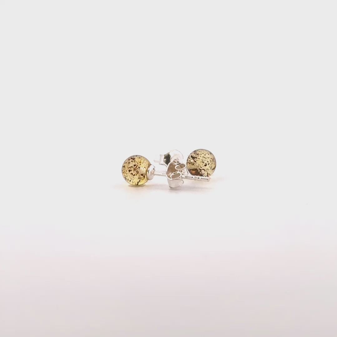 STUDS, Auskarai su natūraliu Baltijos gintaru.   Poliruotos, apvalios formos natūralaus gintaro detalės.  Gintaro diametras: 5 – 7 mm.  Išmatavimai: 5-7mm x 18 mm.  Žalsvai gelsva spalva.  Metalas: Ag 925 Sidabras. 